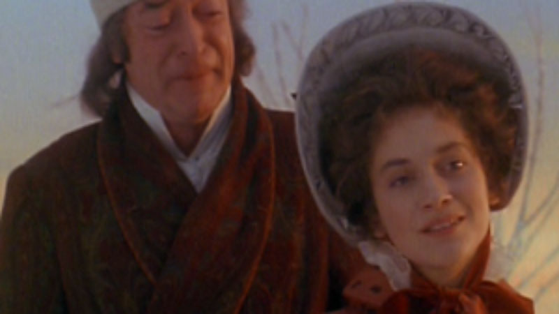 A screenshot from “The Muppet Christmas Carol,” showing Michael Caine as Ebenezer Scrooge standing behind a woman with poofy hair under a Victorian bonnet as she gazes off into the distance. It’s Belle, Scrooge’s former love, and she’s singing about love being gone, and Scrooge is openly weeping, as he should be, as he’s overcome with sadness and loneliness and regret. All of which is right there on Michael Caine’s face.