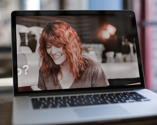A cropped image of a young woman, shown on the screen of a MacBook