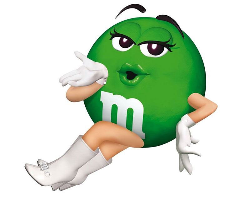 The Green M&Ms mascot lounges seductively, one eyebrow raised suggestively, blowing a kiss at the viewer because a sexy, sex anthropomorphic candy makes SO much sense.