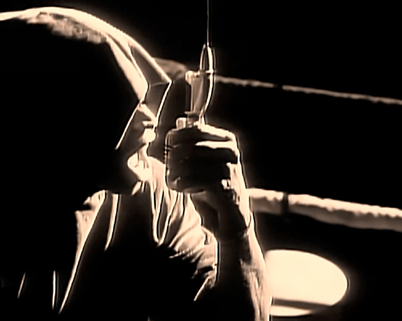 Iconic screenshot from the music video for LL Cool J’ “Mama Said Knock You Out” — a moody, dramatically lit black-and-white shot of Mr. Cool J silhouetted against the ropes of a boxing ring, his face barely visible in the hood of a black sweatshirt, as he holds a boxing announcer’s drop-down microphone and raps about making the tears rain down like a monsoon.