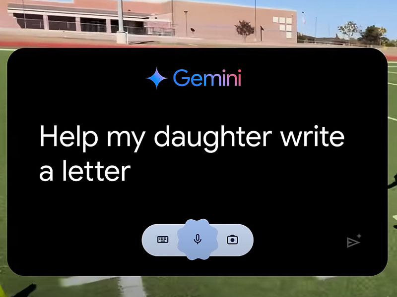 A shot of a track and field facility on a sunny day, with the field house in the background and green grass in the foreground. On top of that, taking up almost the entire frame, is a black box with the Gemini logo at the top and the words “Help my daughter write a letter.”