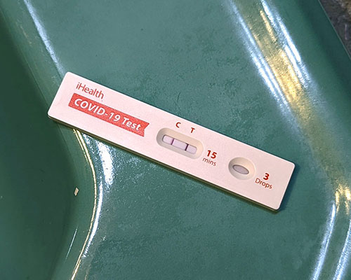 A white COVID-19 test with red letters rests on the edge of a really cute mint-green sink. In the little window, the line under “C” is red. And the line under “T” is black. Yup, this is a positive COVID test. A positive freaking COVID test.