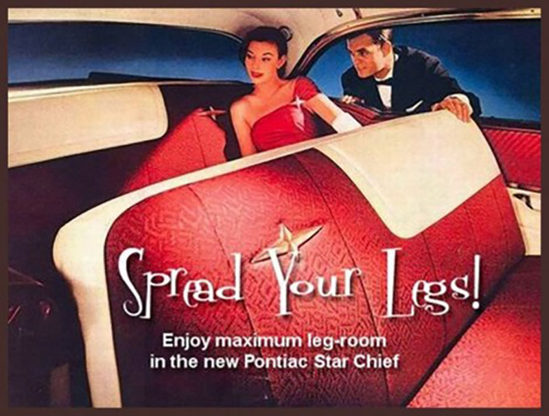 A 1954 Pontiac Star Chief print ad. The image is shot from the inside of a Star Chief, with white-trimmed red leather seats. A brunette woman in a red gown and white gloves is sitting in the back seat, just visible from the camera’s vantage point next to the front seat. A brunet man in a tuxedo is leaning in through the car window next to her. The headline reads, in white letters, “Spread your legs!” The copy reads, “Enjoy maximum leg-room in the new Pontiac Star Chief.”