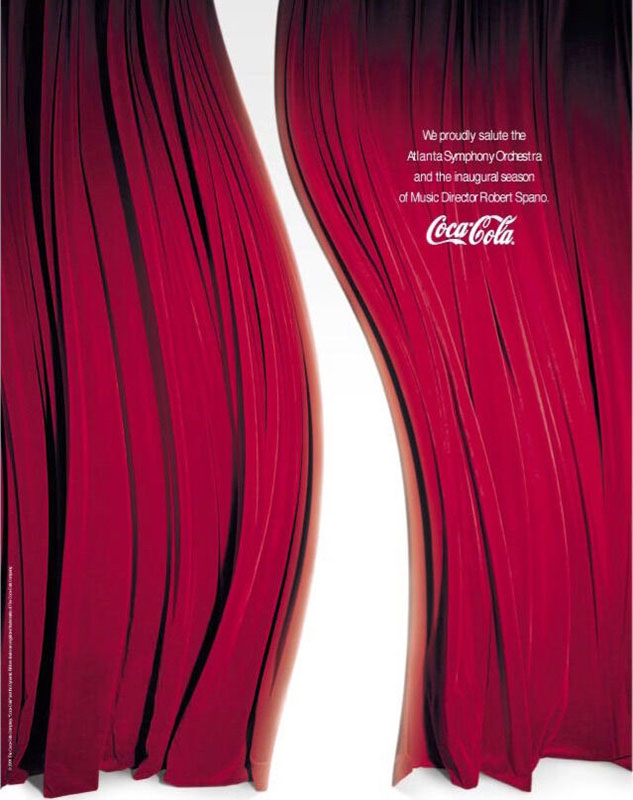 A Coca-Cola print ad from an issue of the Atlanta Symphony Orchestra Playbill. The ad shows red velvet curtains against a glowy white background, with the parting in the curtain mimicking the shape of the Coca-Cola swoop (vertically). Copy, in small white type against the red curtain, reads, “We proudly salute the Atlanta Symphony Orchestra and its inaugural season of Music Director Robert Spano,” followed by the Coca-Cola logo.