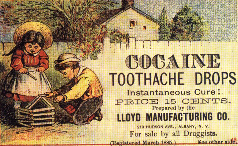 A very old, yellowed ad with an illustration all the way to the left of two children outside, building a small cabin out of sticks. They’re standing against a white fence with a house and trees visible on the other side. To the right of them are the words, in large, decorative text, “Cocaine Toothache Drops.” Below it, in smaller text, are the words, “Instantaneous Cure! Price 15 Cents. Prepared by the Lloyd Manufacturing Co. 2019 Hudson Ave., Albany, N.Y. For sale by all Druggists. (Registered March 1885) See other side.”