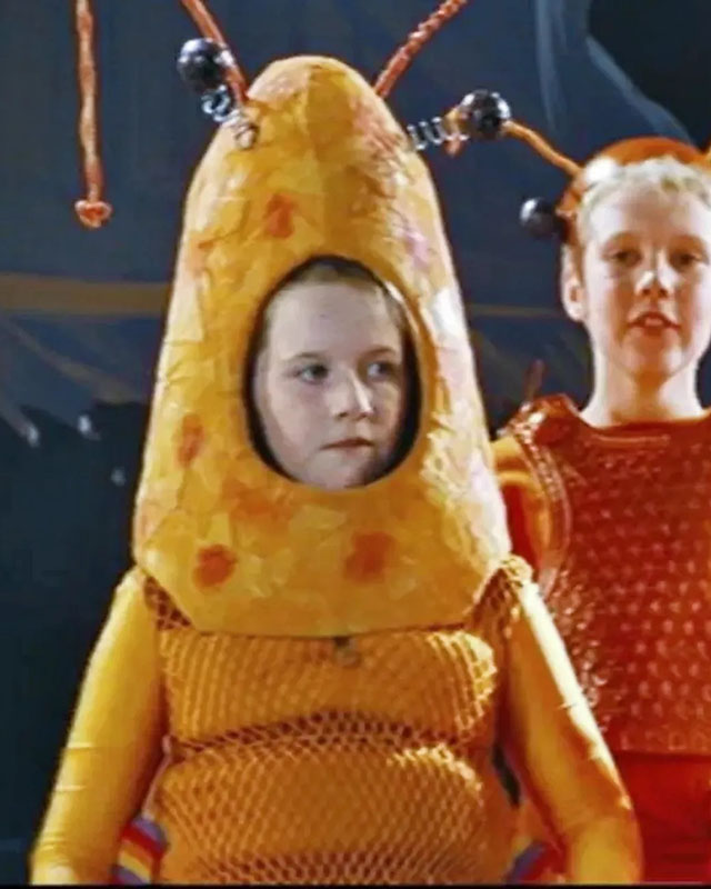 A cropped screenshot from the movie “Love, Actually,” showing a young girl in an orange papier-mache lobster costume, looking uncertainly at something just out of frame to the right. A young boy in a similar costume stands behind her and to the right, looking out at the audience not-uncertainly.