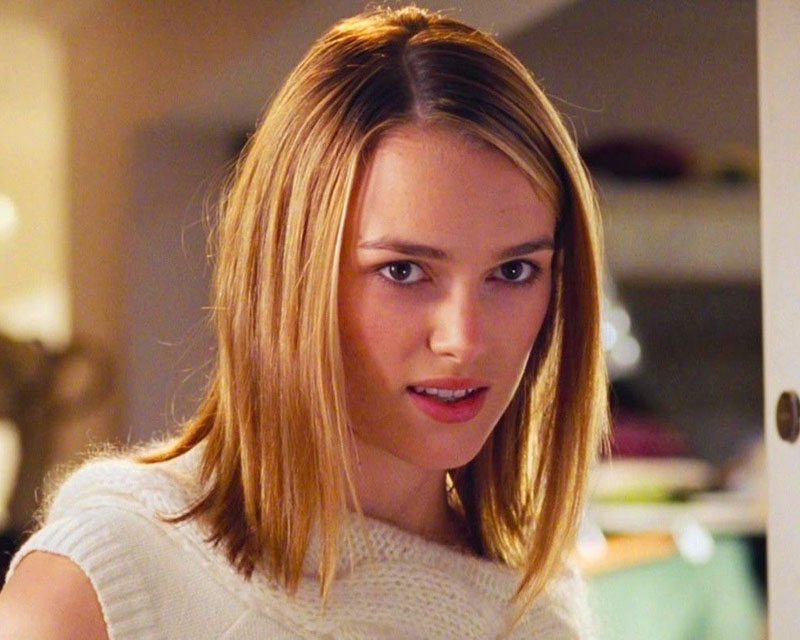 A cropped screenshot from the movie “Love, Actually,” showing a young woman with shoulder-length blonde hair, a white sleeveless sweater, and an uncertain/somewhat creeped-out look on her face.