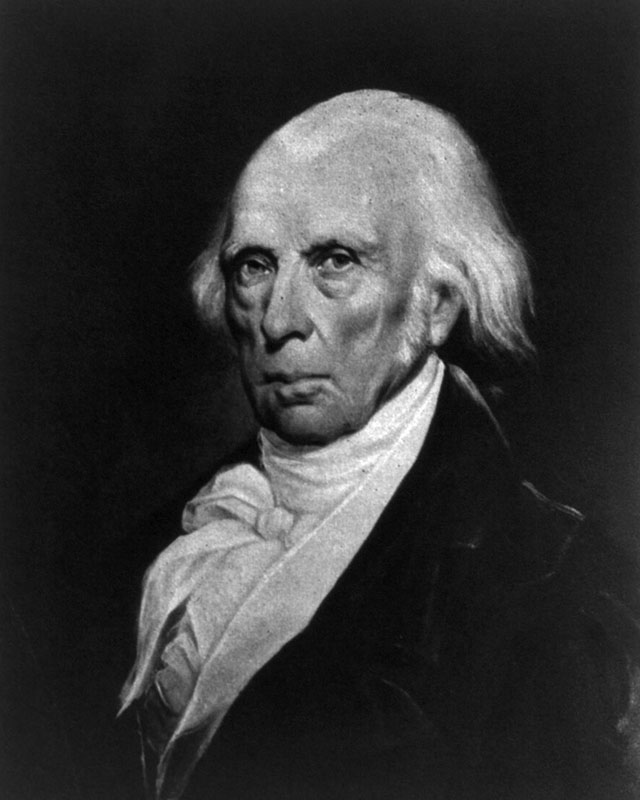 Oil painting of James Madison, an extremely old, balding white man with white hair trailing off on the sides, a black high-collared jacket, a puffy white cravat, and an expression like he’s trying to keep a swarm of bees from escaping his mouth.